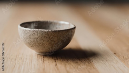 Small, light beige ceramic bowl on a light wooden surface