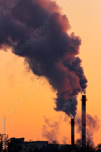 Foto Heavy steam billows from industrial chimneys against a fiery winter sunset, high