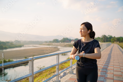 Asian woman checking smartwatch while walking outdoors. Virtual fitness assistant technology.