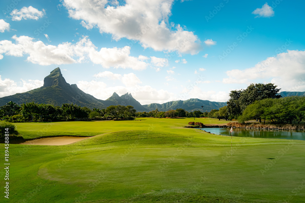 Obraz premium Panoramic Golf Course with Majestic Mountains and Tranquil Lake at Golden Hour