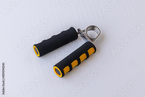 Fotografie Hand grip strengthener with black and yellow foam handles on a white background