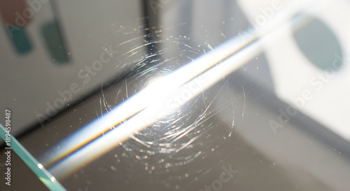 Macro shot showing circular scratches on a transparent glass surface with light refraction creating a subtle rainbow effect