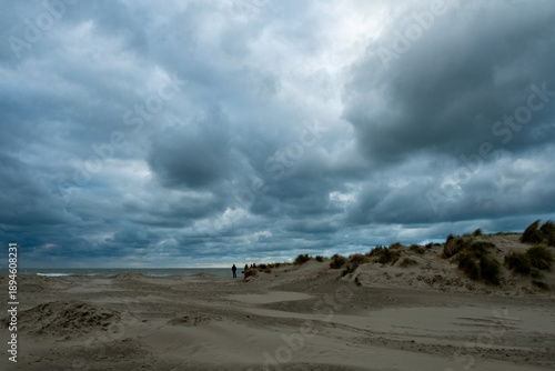 breezy dunes and solitary travelers by sea, overcast skies overshadow quiet journey along sandy