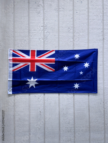 Australian flag hanging on white wood panel wall with space for text