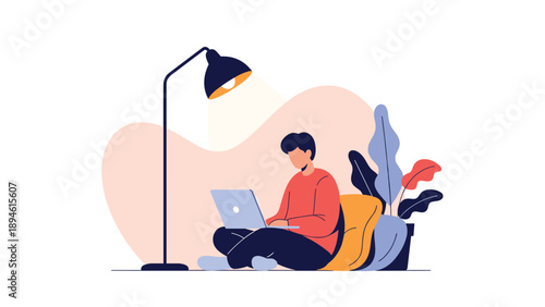 A young man works or studies on his laptop while sitting comfortably on the floor under the light of a lamp in a cozy home environment.