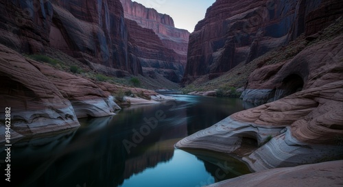 Majestic canyon landscape at dusk, featuring a serene river mirroring towering stratified rock formations and their dramatic natural shadows