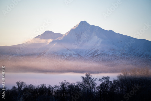 Konstfotografi Mount Shari at sunrise in winter, Hokkaido, glowing softly above misty snowfield