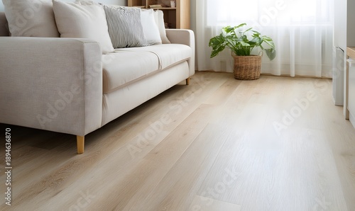 A corner of a modern living room, with light wood flooring, next to a corner of a light beige sofa, bright and spacious.