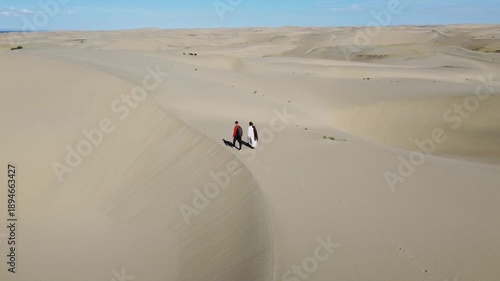 People walking through the desert, aerial photography, view of the dunes from above
