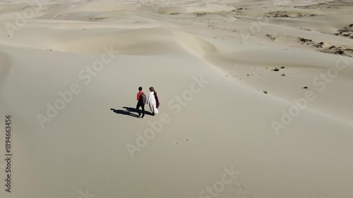People walking through the desert, aerial photography, view of the dunes from above
