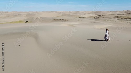 People walking through the desert, aerial photography, view of the dunes from above
