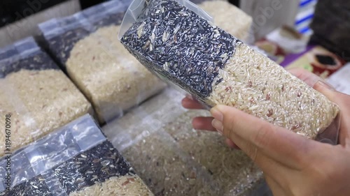 Hands holding and choosing packaged organic rice in store. Consumer rice choice, food ingredient, rice varieties, grocery shopping and everyday lifestyle concept