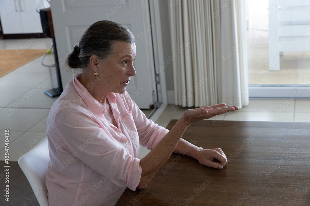 Fototapeta premium Wooden dining table sitting next to sliding glass door with soft light filtering curtains