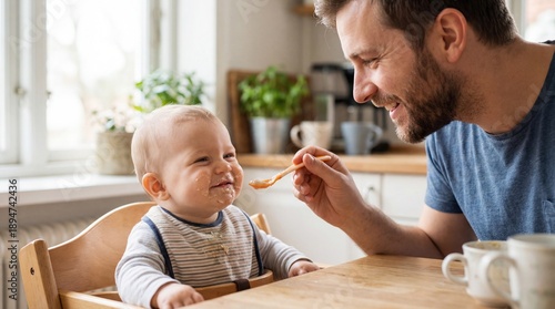 A heartwarming moment captures a father feeding his smiling baby with a spoon, symbolizing the everyday love and joy of parenthood. The scene takes place in a sunlit kitchen.