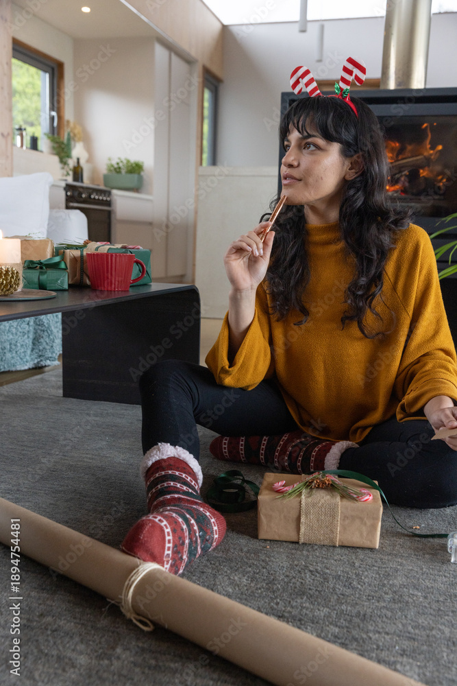 Obraz premium Asian woman sitting in home holding cinnamon stick staring wrapping gifts with kraft paper