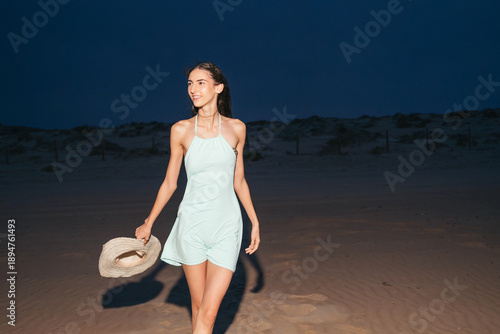 Bild auf Leinwand Smiling woman walking on beach at night