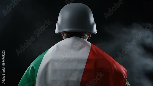 Soldier in helmet with italian flag standing against dark background