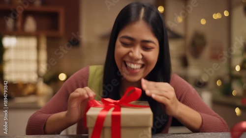 Woman opening gift indoors smiling