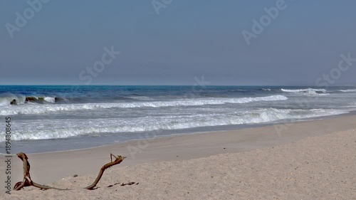 Sunny Atlantic beach with calm sea and footprints in sand under clear sky, Portugal, Praia da Gaivinia, 13 October 2025
