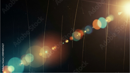 Rainbow lights and rain falling down on a dark background with lens flares from the top right