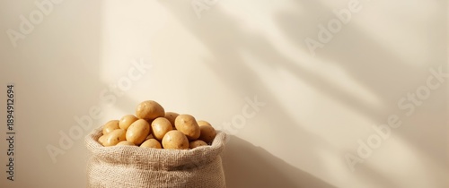 Raw potatoes inside a burlap sack with a light backdrop