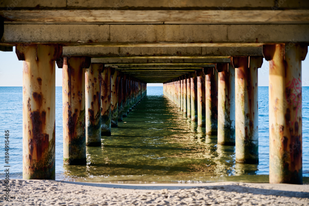 Obraz premium Rusty pier columns over Baltic Sea waters at sunset