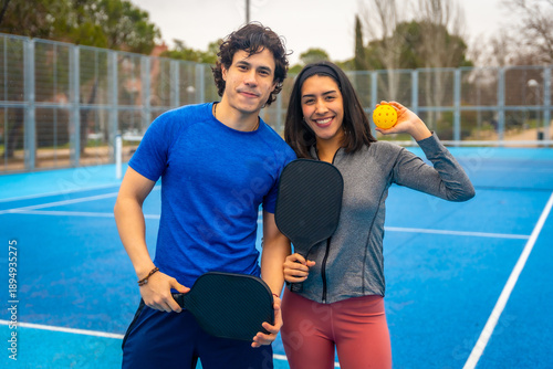 Young couple enjoying time playing pickleball outdoors