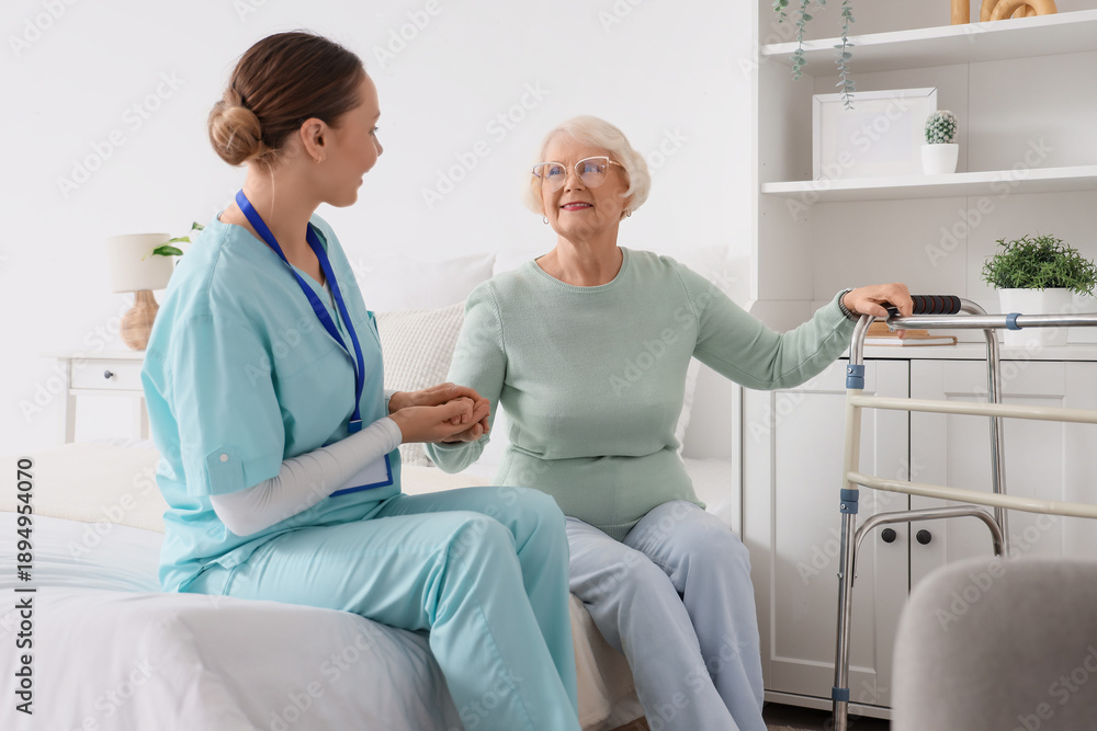 Obraz premium Nurse and senior woman sitting on bed