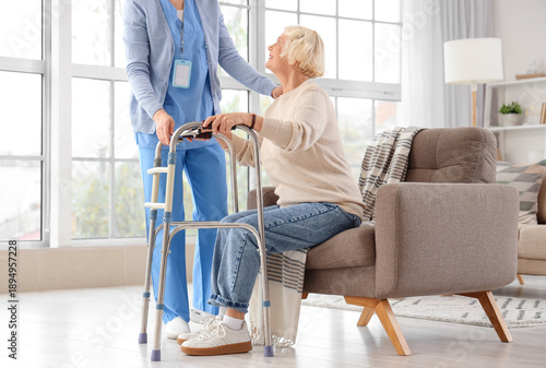 Canvas Print Nurse helping senior woman with walker to get up from armchair