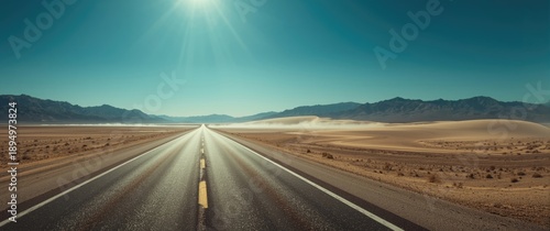 Classic vertical perspective of an endless straight road in the barren scenery of renowned Death Valley, featuring extreme heat haze on a bright sunny summer day with blue skies in California, USA