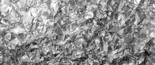 Shiny and tinted crumpled aluminium foil backdrop with faceted, textured appearance