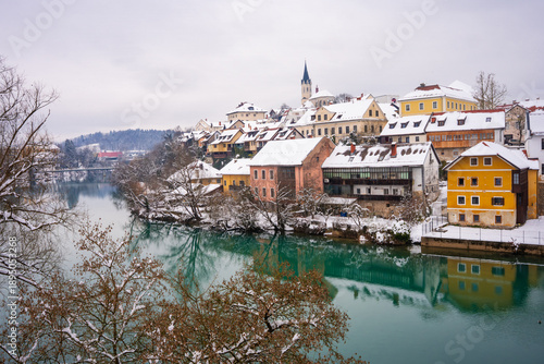 Foto The picturesque town of Novo Mesto in Slovenia during winter, covered in snow, showing beautiful facades and houses along the colorful Krka River