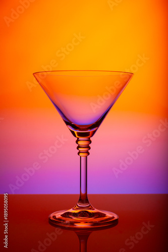 Minimalist martini glass against vibrant gradient backdrop, reflective surface, luxury cocktail stemware, modern bar design, clean studio photography, colorful nightlife mood