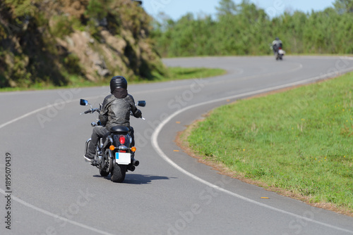 Fotografie biker on a custom classic motorcycle rides down the road, road traffic