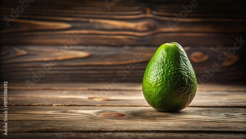 A single ripe avocado rests on a rustic wooden surface, showcasing its vibrant green skin and natural texture.
