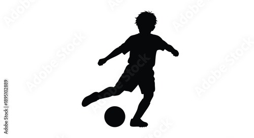 A young boy playing soccer captured in a striking silhouette