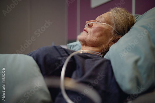 Canvas Print Senior Asian woman lying in hospital bed receiving oxygen therapy through nasal