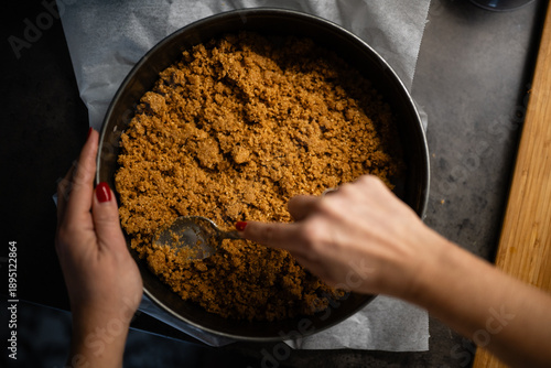 Foto Hands pressing graham cracker crust into springform pan