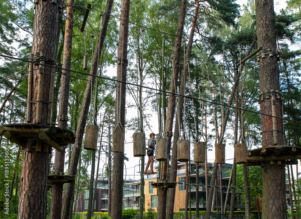 Fototapeta premium Active Boy Overcoming Rope Course Obstacles in Adventure Park