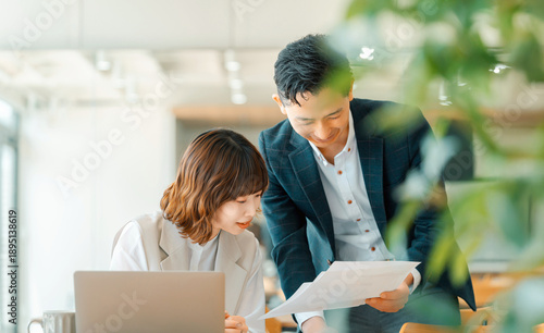 オフィスで資料を確認する上司と部下の打ち合わせシーン, Manager and junior staff reviewing documents together in office