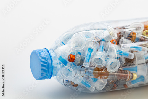 Used insulin syringes in plastic bottle for infectious waste disposal, medical biohazard waste management and safety concept