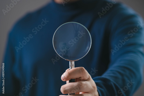 Fotografie Hand holding magnifying glass on clean background, representing search, analysis, investigation, research, focus, inspection, transparency, problem solving, and business or technology concept