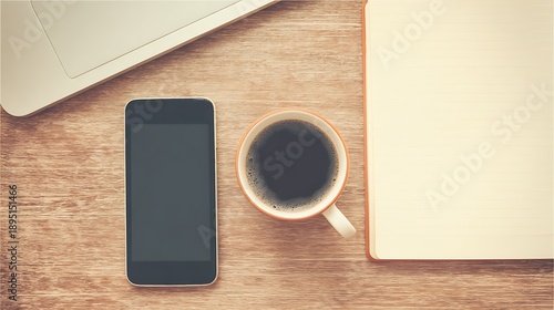 Top down view of a rustic wooden desk with a laptop, smartphone, coffee cup, and open notebook for work or study