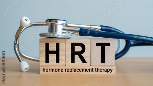 Wooden blocks spelling HRT with a stethoscope and text hormone replacement therapy on a wooden table surface