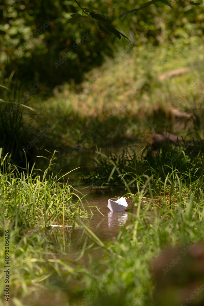 Obraz premium A small, gentle stream gracefully winds its way through a vibrant, lush green field, while trees stand majestically in the background