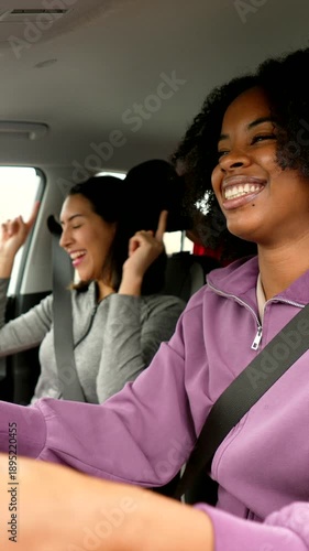 Happy female friends singing and dancing in car during road trip