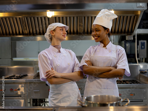 Wallpaper Mural Two women chef coworkers standing confidently with crossed arms in professional kitchen smiling at each other; teamwork leadership hospitality career pride Torontodigital.ca