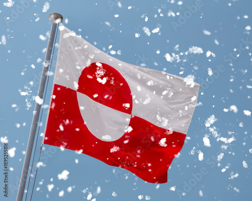 Greenland the Greenlandic national flag waving in snow weather on a flagpole with blue sky background.