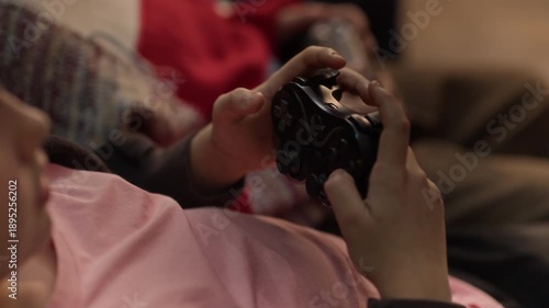 Close up of two unrecognizable boys resting on comfortable sofa and playing co-op video game at home