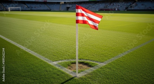 Corner flag on soccer field in vibrant green grass with red and white stripes in bright sunny lighting for sports event